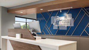 A modern hotel reception desk with a blue geometric wall design, a sign for Holiday Inn Express & Suites, and a computer on the desk. - Holiday Inn Express and Suites Rhinelander by IHG (Rhinelander)