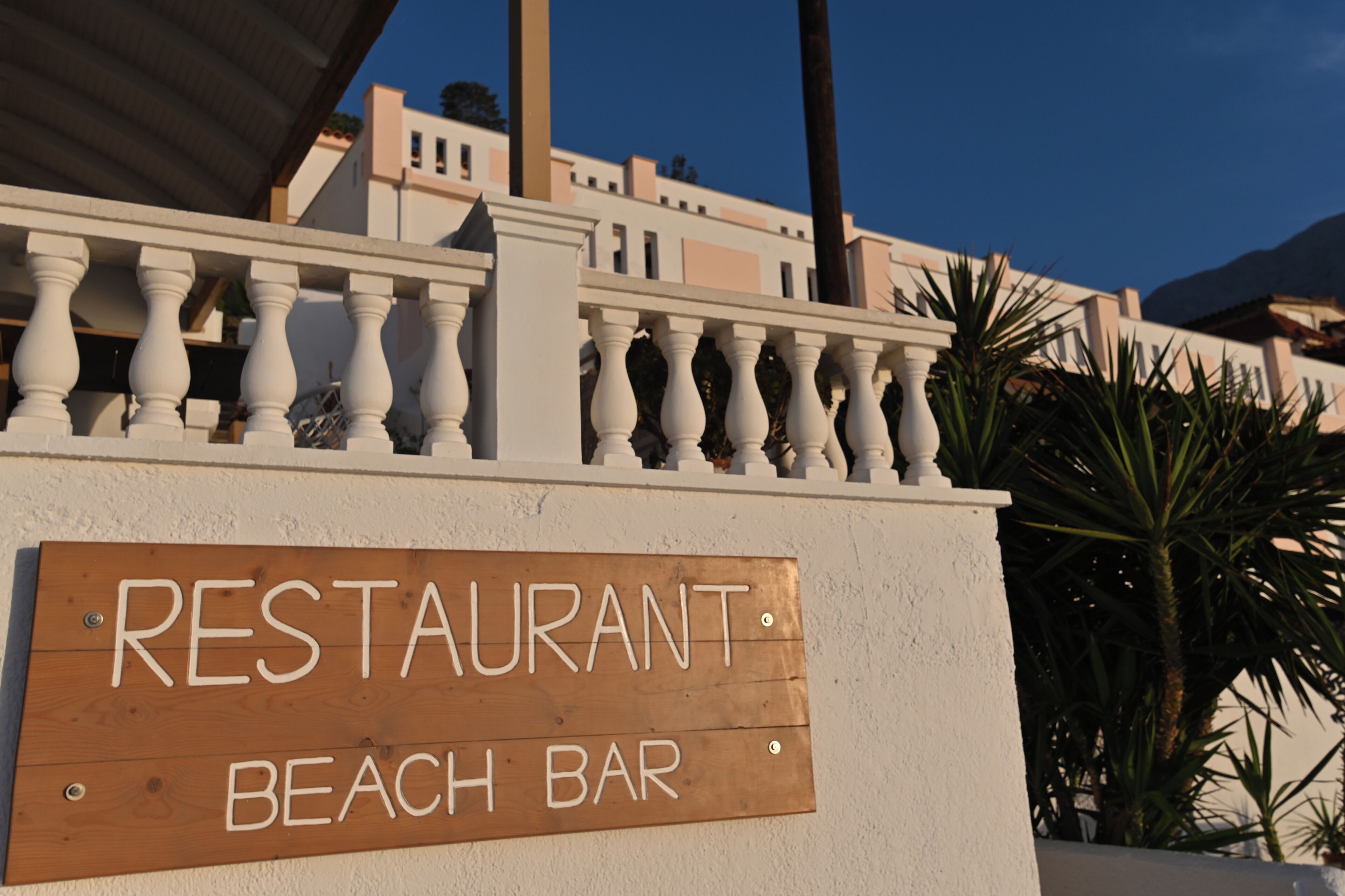 A wooden sign with 'RESTAURANT BEACH BAR' written on it.