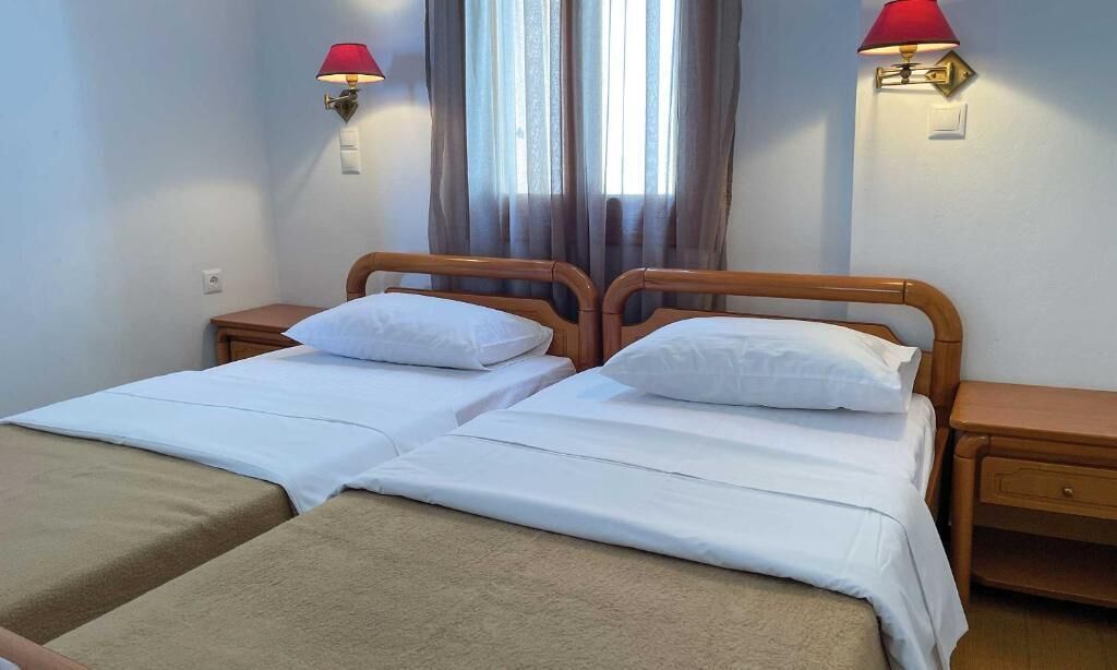A double bed with a wooden headboard, two bedside tables, and two wall-mounted lamps.