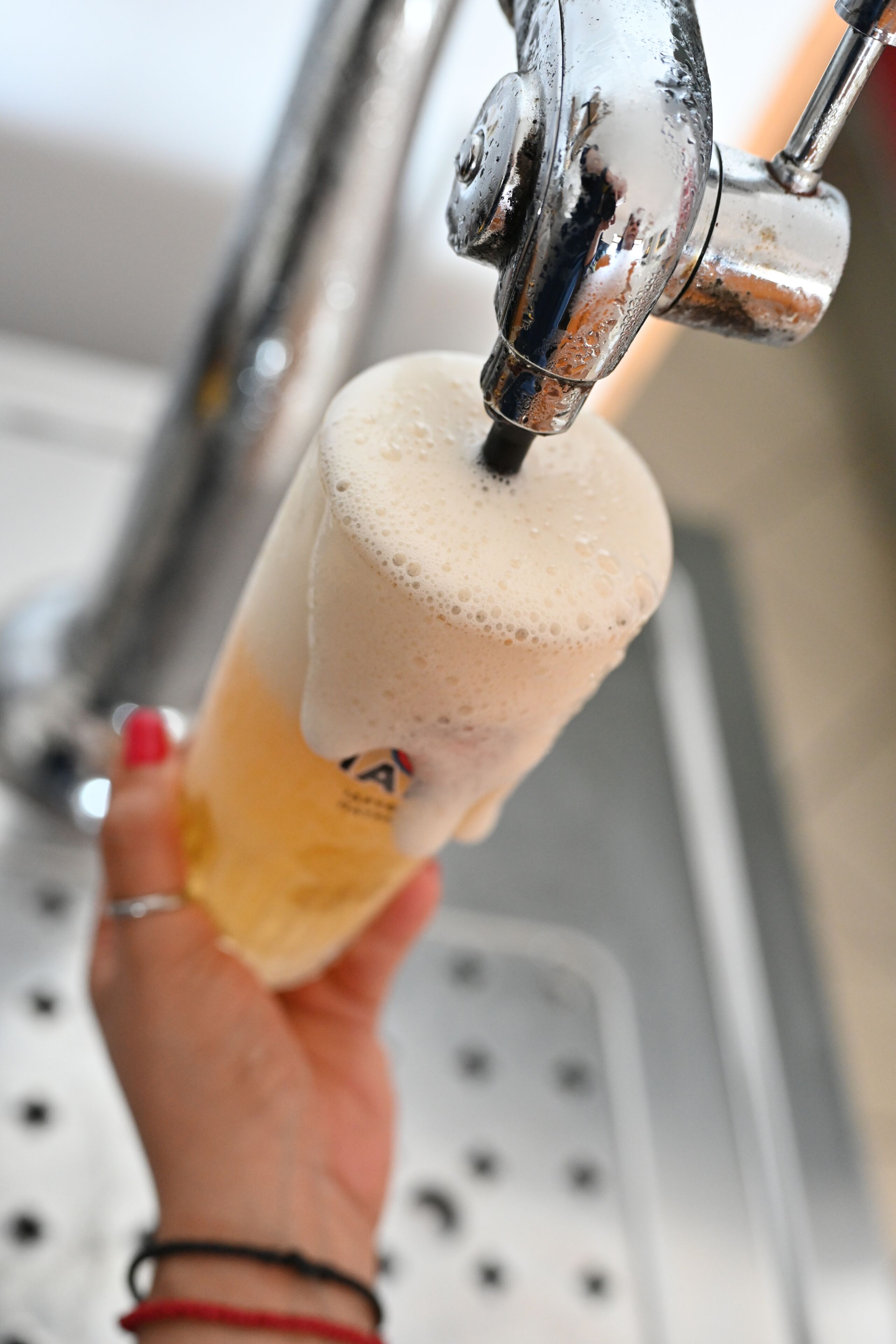 A hand holding a beer mug under a tap with foam.