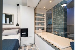 A modern bedroom with a bed, bedside table, and a large mirror. - Apartments Villa Arcadia (Dubrovnik)