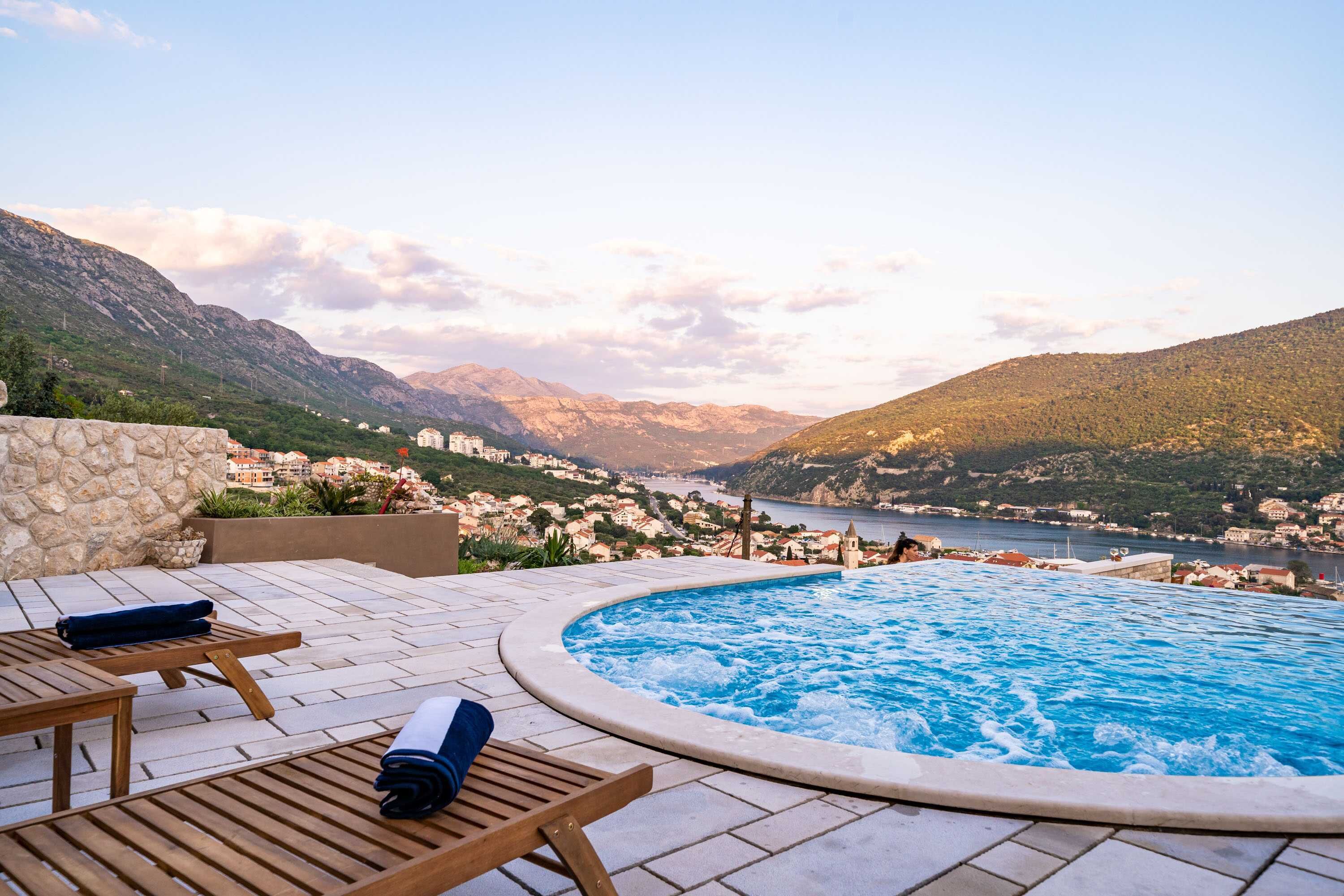 A pool area with lounge chairs and a view of a mountainous landscape.