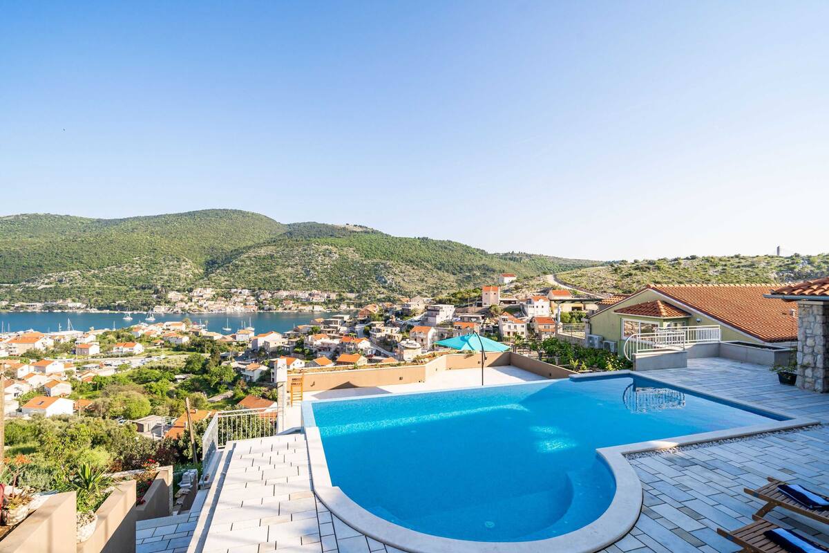 Una piscina con vistas a un pueblo costero y colinas.