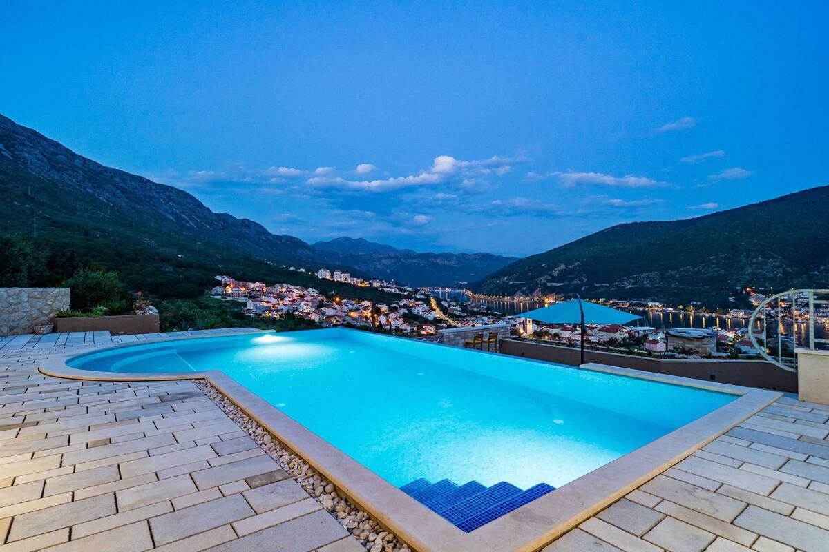 Una piscina con vista a un pueblo y montañas al fondo.
