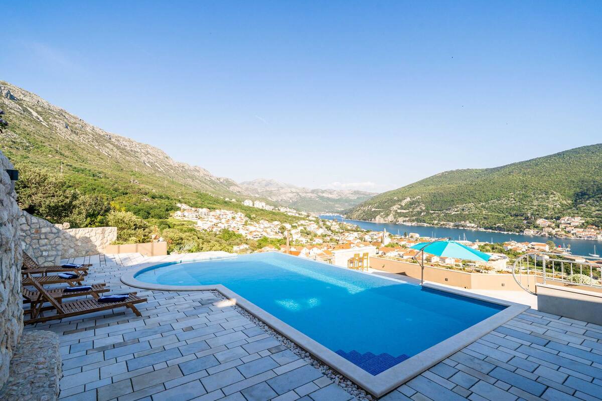 Una piscina con vistas a un pueblo costero y montañas.