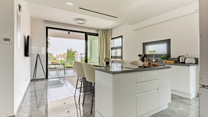 A modern kitchen with a central island, white cabinetry, and a view to the outside. - Sanders Evolution 2 Lovely 2 Bedroom Apartment With Balcony (Limassol)