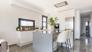 A modern kitchen with a central island, white cabinetry, and a large window. - Sanders Evolution 2 - 2 Bedroom Apartment With Private Rooftop and Jacuzzi (Limassol)
