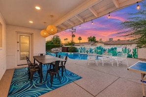 An outdoor patio with a pool, seating, and a mural.