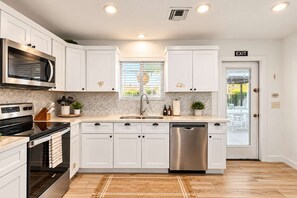 A modern kitchen with white cabinetry, stainless steel appliances, a built-in microwave, and a dishwasher. - Vacay on Villa | Old Town |Swim, Putt, Play & Stay (Scottsdale)