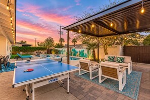 An outdoor pool area with a ping pong table, lounge chairs, and a covered seating area. - Vacay on Villa | Old Town |Swim, Putt, Play & Stay (Scottsdale)
