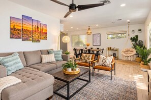 A modern living room with a sofa, coffee table, and chairs, a dining area with a table and chairs, and a ceiling fan. - Vacay on Villa | Old Town |Swim, Putt, Play & Stay (Scottsdale)