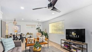 Ein modernes Wohnzimmer mit Sofa, Couchtisch, TV-Möbel und Deckenventilator.