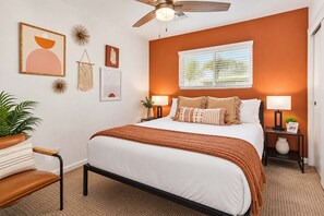 A bedroom with a bed, bedside tables, a ceiling fan, and wall decorations.