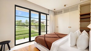 Een slaapkamer met een grote schuifpui, een bed met wit en bruin beddengoed, een houten vloer en een inbouwkast met planken.