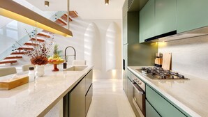 Een moderne keuken met een centraal eiland, roestvrijstalen apparatuur en een groene spatwand.