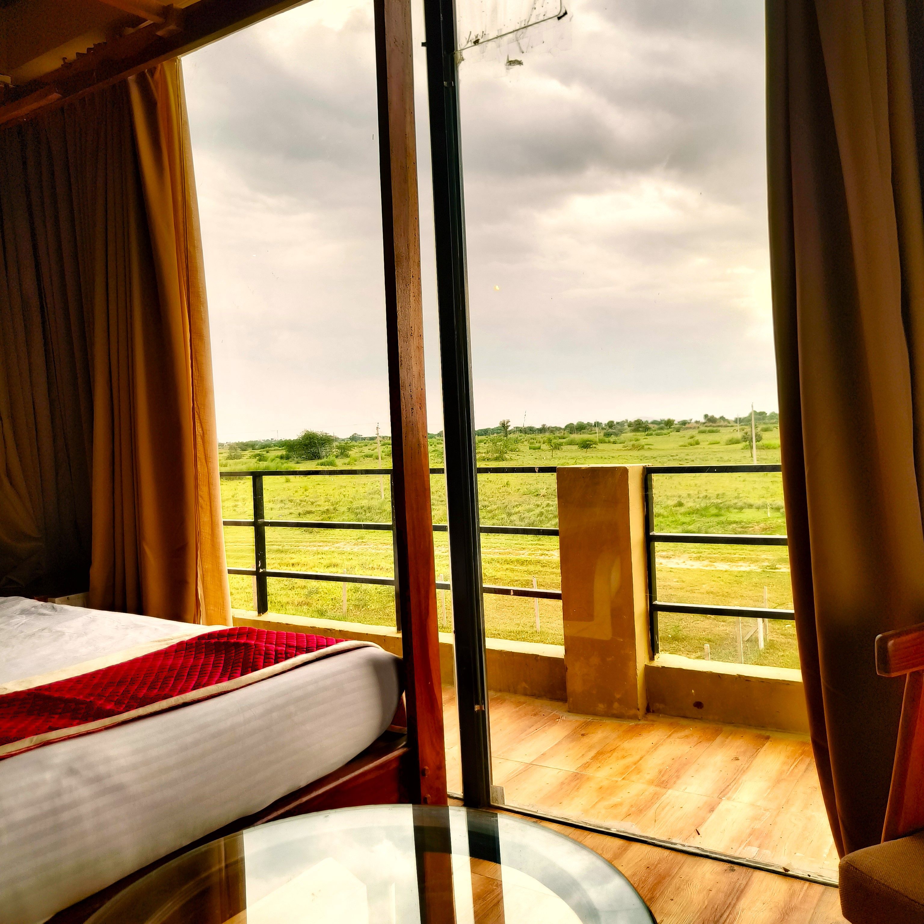 Una habitación con cama, una mesa y vistas a un campo cubierto de hierba a través de una ventana.