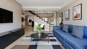 Ein modernes Wohnzimmer mit einem blauen Sofa, einem schwarzen Couchtisch und einem Flachbildfernseher.