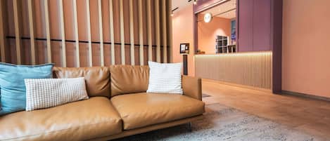 A modern reception area with a reception desk, a sofa with cushions, and a patterned rug.