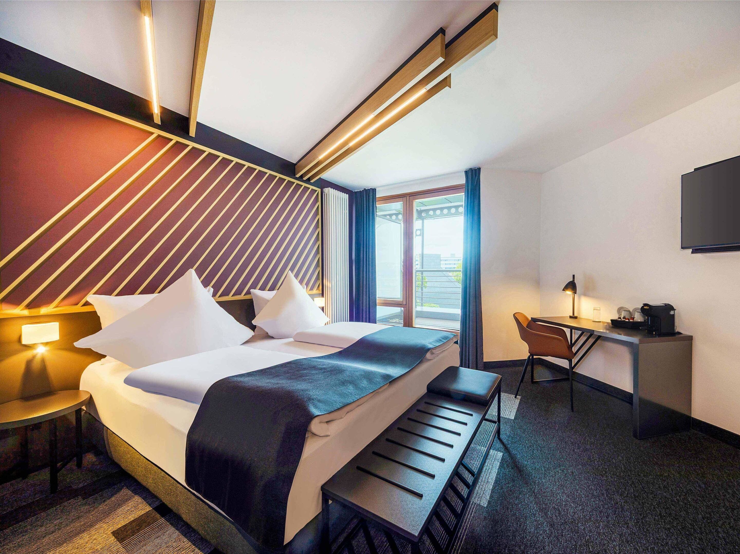 Una habitación de hotel moderna con cama, escritorio y zona de estar.