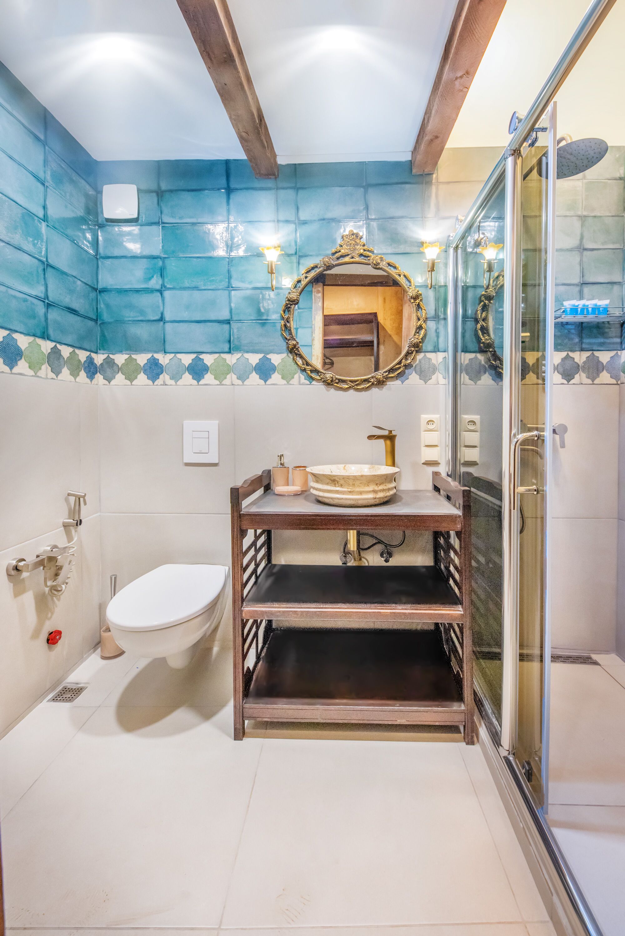 A bathroom with a white toilet, a wooden vanity with a round sink, and a glass shower enclosure.