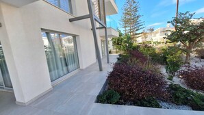 A modern building with a flat roof, large windows, and a paved walkway. - Emerald Bay Suites (Paralimni)