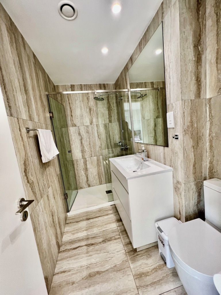 Une salle de bain moderne avec une douche à parois de verre, un lavabo blanc et des toilettes.