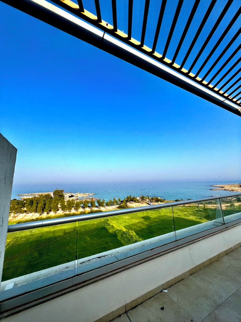 A balcony with a clear view of the sea and a distant shoreline.