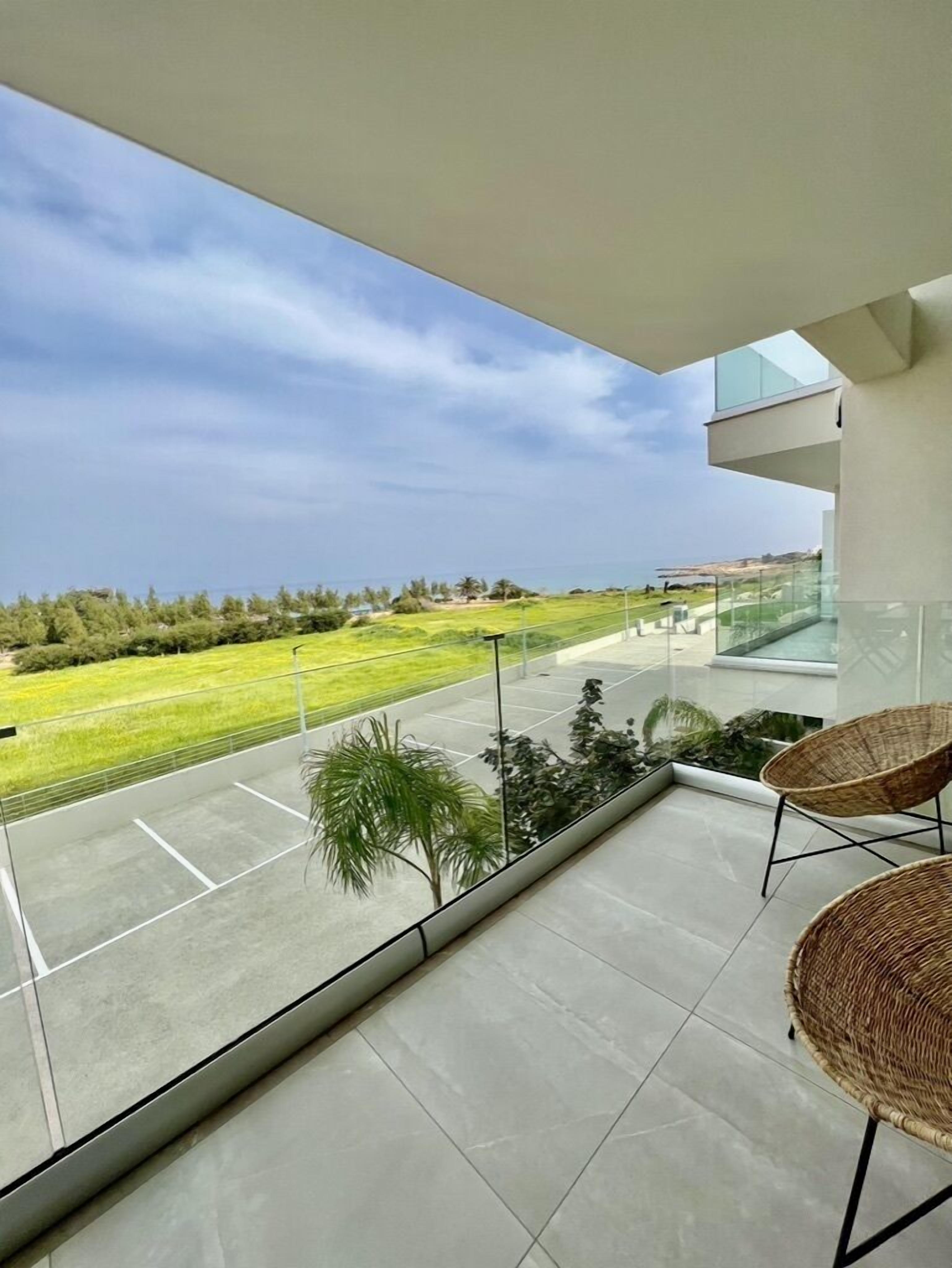 A balcony with a view of a green landscape and a clear sky.