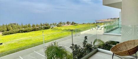A balcony with a view of a green landscape and a clear sky.