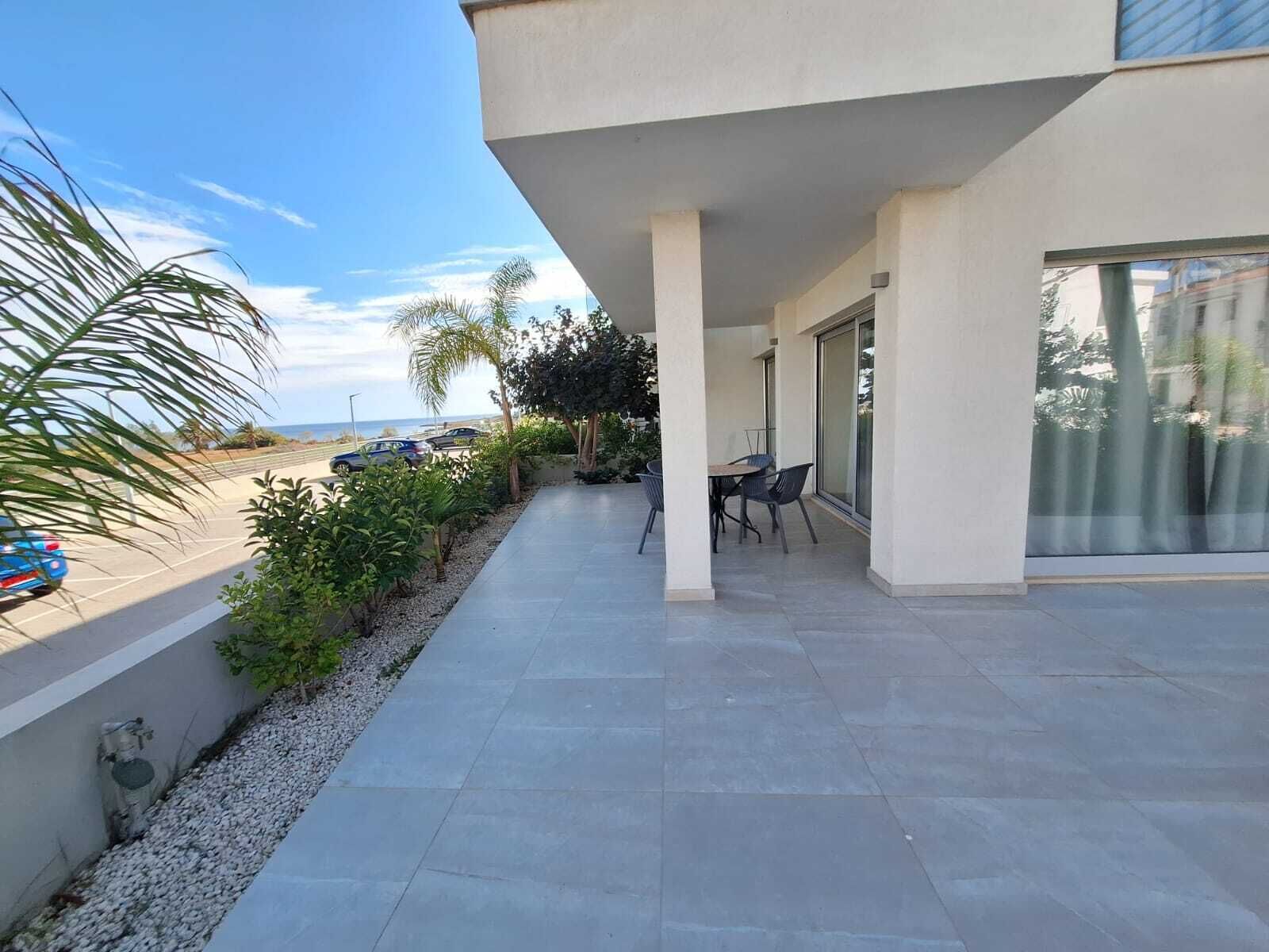 Eine moderne Terrassenanlage im Freien mit Sitzgelegenheit, Blick ins Schwimmbecken und blauem Himmel.