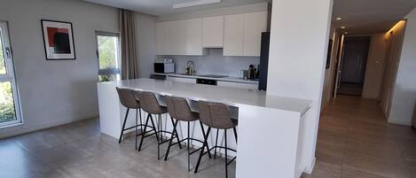 Una cocina moderna con una isla central, taburetes de bar y vistas al área de comedor.