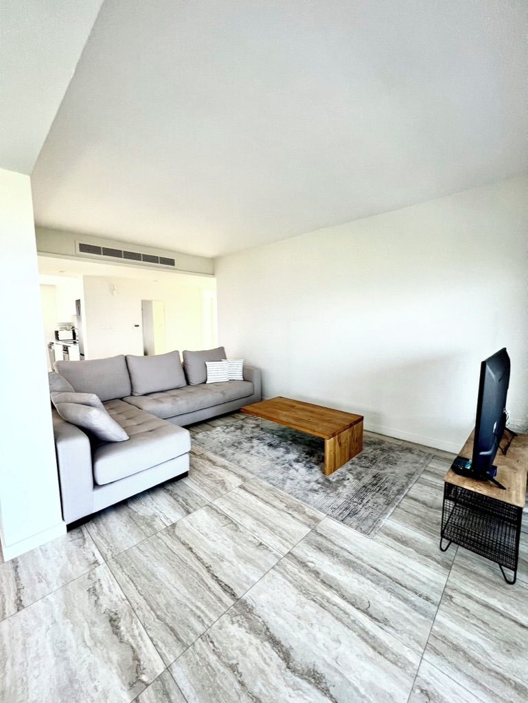 A modern living room with a sectional sofa, a wooden coffee table, and a television on a stand.
