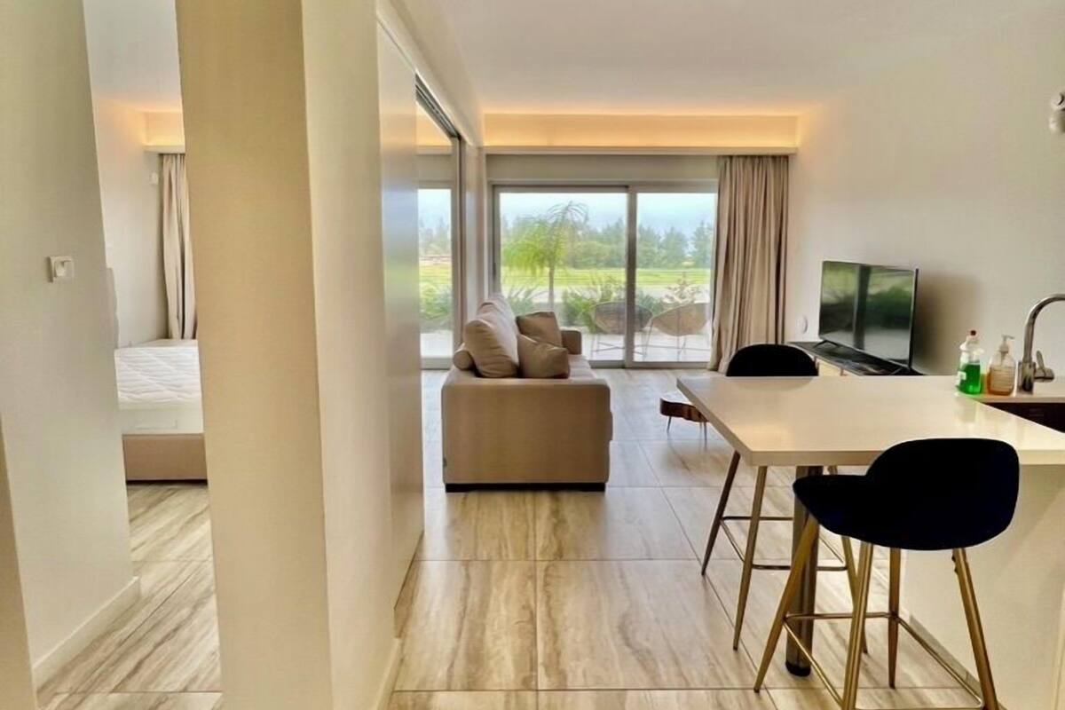 A modern living room with a sofa, a dining table, and a TV.