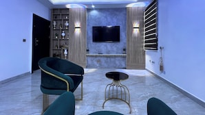 A modern living room with a flat-screen TV, a fireplace, and a decorative shelf. - GRACIAS HOTEL AND SUITES (Lekki)