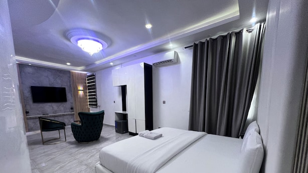 A modern hotel room with a large bed, a desk, a chair, and a TV mounted on the wall. - GRACIAS HOTEL AND SUITES (Lekki)