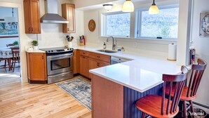 A modern kitchen with wooden cabinets, stainless steel appliances, a large island, and pendant lighting.