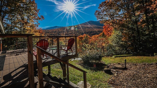 A deck with chairs overlooking a mountainous landscape.