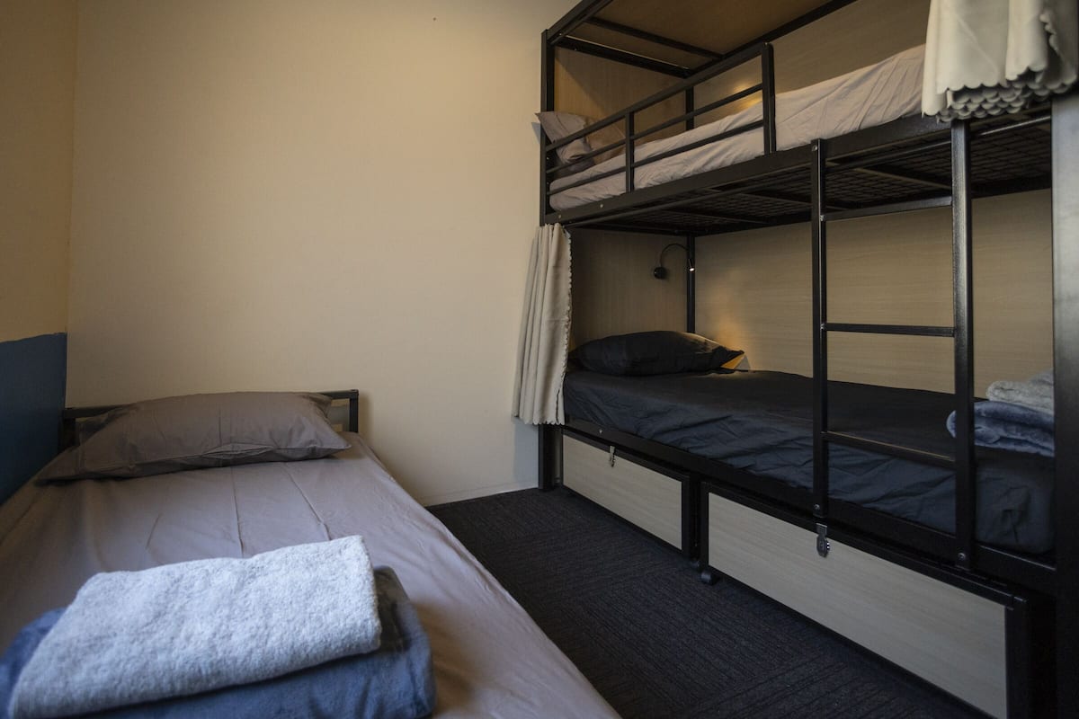 A bunk bed room with a single bed on the left and a bunk bed on the right.