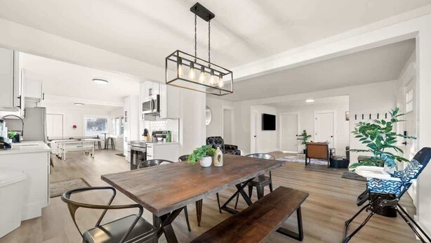A spacious living area with a wooden dining table, benches, and a hanging light fixture. - Newly Renovated Comfy Retreat (Spokane)