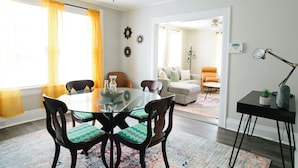 A dining area with a glass table and chairs, a sofa, and a lamp.