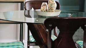 A dining area with a glass table, wooden chairs, and a bowl with decorative items.