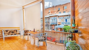 A wooden balcony with a table and chairs, a bench, and potted plants. - H&B apartments Qolga (Tbilisi)