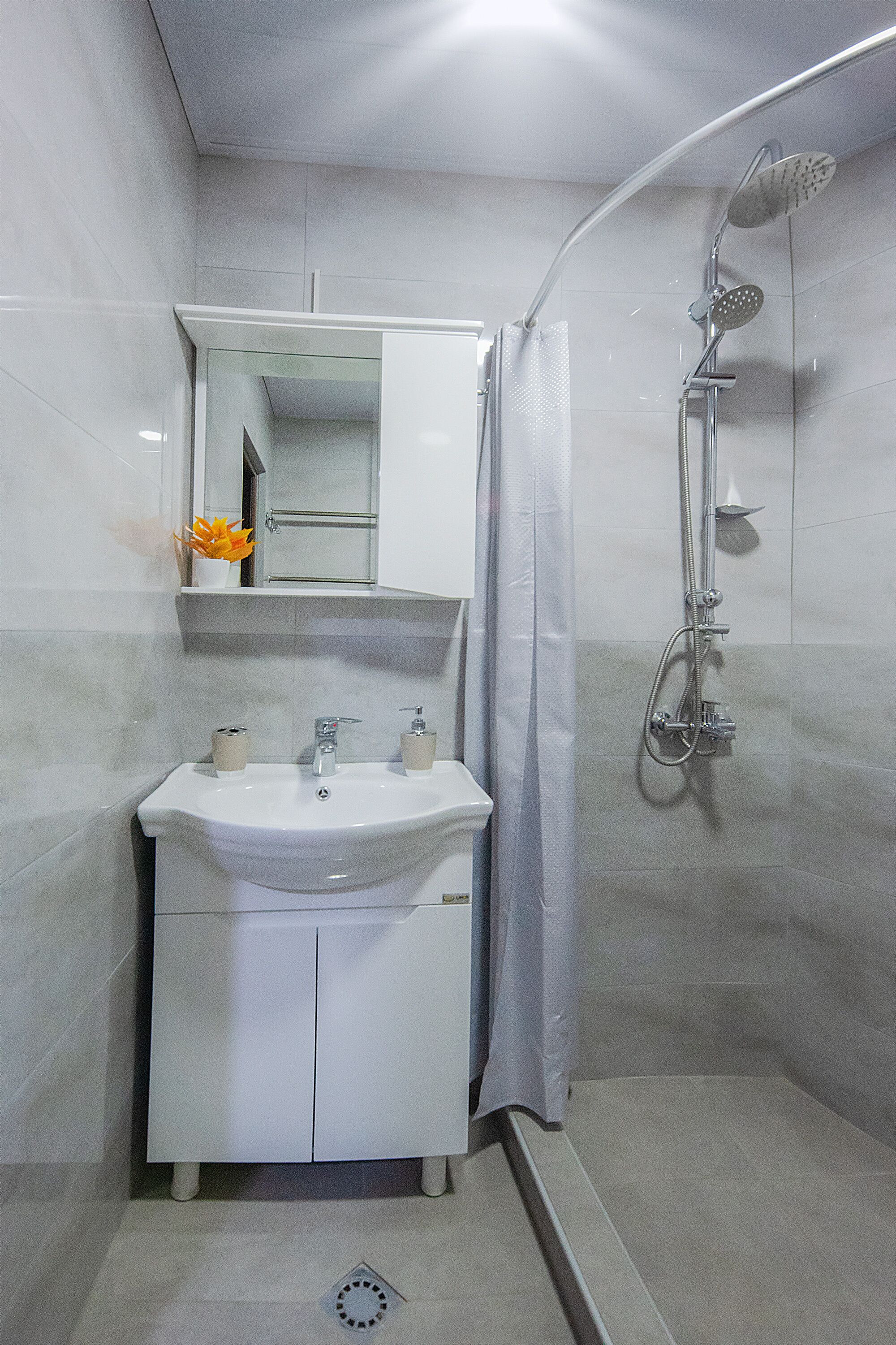 A modern bathroom with a white sink, mirror, and shower.