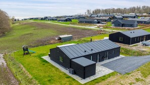 Zona residencial con casas modernas, un parque infantil y un amplio campo abierto.