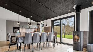 Una cocina moderna con comedor, ventanas amplias y una estufa de leña.