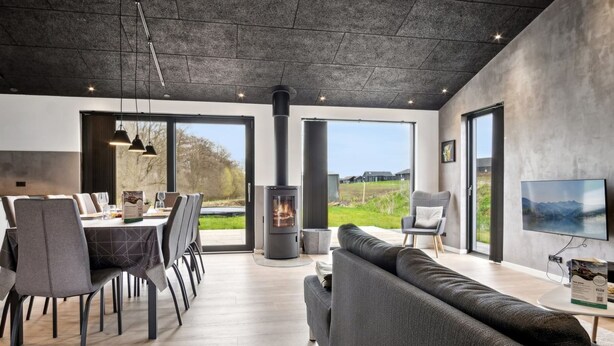 Una sala de estar moderna con chimenea, un comedor y un amplio ventanal con vistas al exterior.