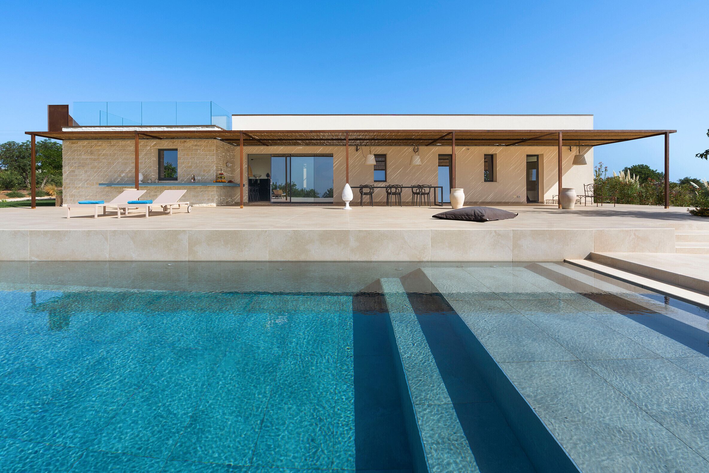 A modern house with a swimming pool, outdoor seating, and a covered patio.