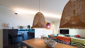 Eine moderne Küche mit dunklen Schränken, einem Holztisch und hängenden gewebten Leuchten.