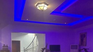A modern interior with a staircase leading to another room, a dining area with a unique wooden sculpture centerpiece, and a ceiling light fixture. - TAI HOTEL LEKKI (Lekki)