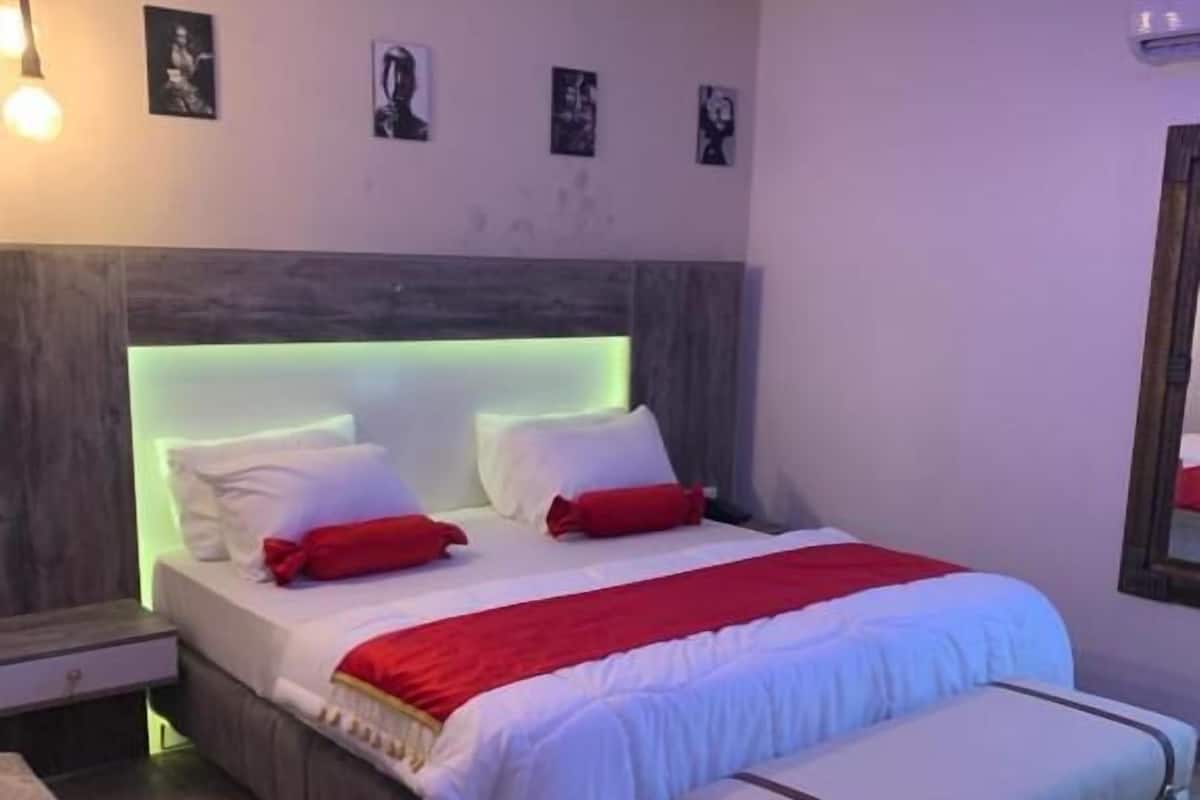 A modern bedroom with a bed, bedside tables, a nightstand, a bench, and wall art.
